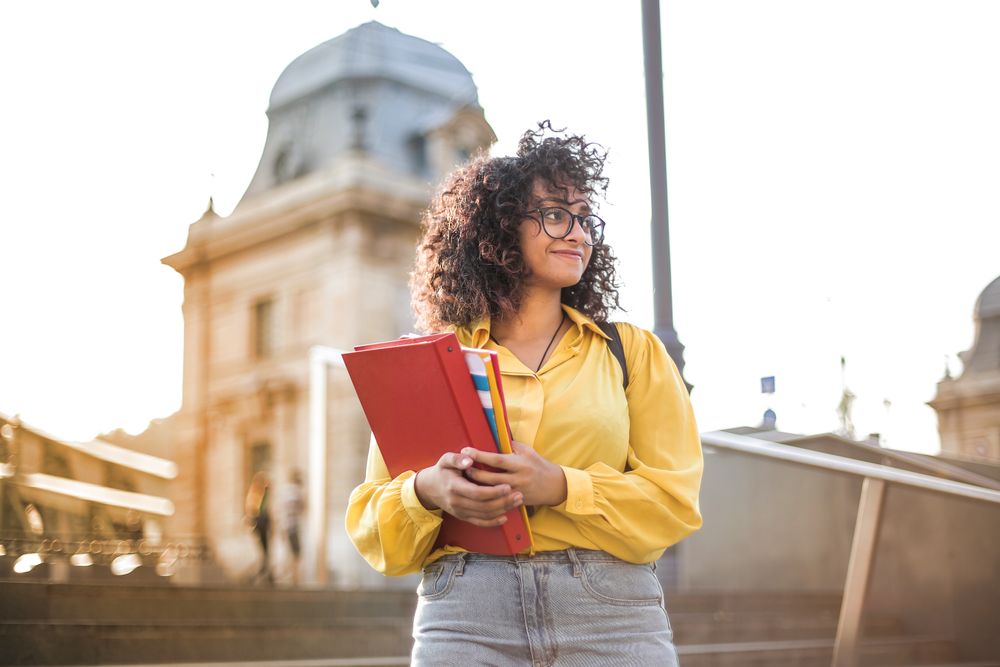 Student holding books on campus steps